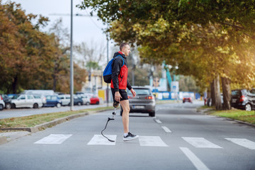 Full length of handsome caucasian handicapped sportsman in sportswear, with artificial leg and...
