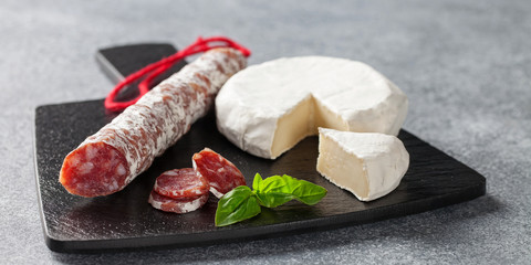 Spanish fuet sausages cut in slices , cheese Brie and basil