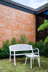 white chair in garden with brick wall background