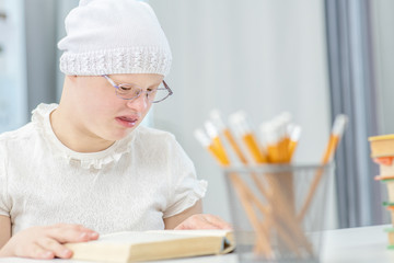 Smart girl with Down Syndrome read book at school