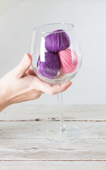 Eco-friendly cotton yarn. Skeins of purple and pink yarn in a glass goblet. Items for female...