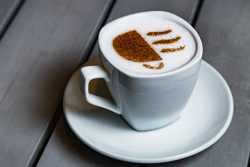 cup of coffee with cream on wooden background