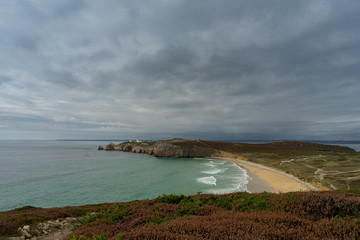 a colorful coastal area with rocks and dark rain clouds - 295574637