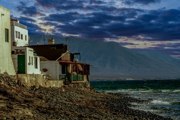 A small fishing village on the coast with dark rain clouds at sunset - 295574854