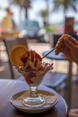 A sundae with many strawberries in a street cafe and a woman's hand - 295575004