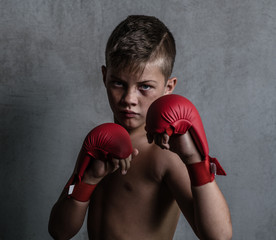 Beaten young boy punching with red boxing gloves