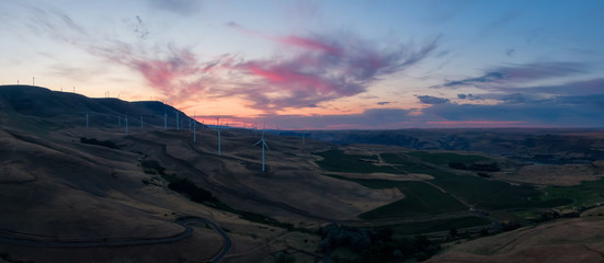 Beautiful Aerial Panoramic Landscape View of Wind Turbines on a Windy Hill during a colorful sunrise. Taken in Washington State, United States of America.