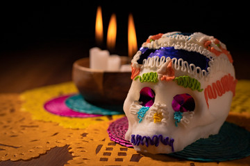 Sugar skull with burning candles and colored papers