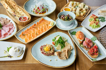 Beef tartar in the restaurant. Variety of dishes on the table. Various snacks and antipasti on the table. Restaurant menu. Italian cuisine