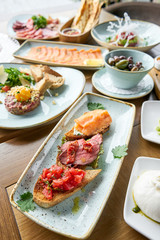 Bruschetta with beef, tomatoes and salmon.. Variety of dishes on the table. Various snacks and antipasti on the table. Restaurant menu. Italian cuisine