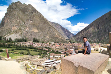 Tourist observing the city with a panoramic view in Ollantaytambo is a town in the Sacred Valley of Peru, which lies south on the Urubamba River and is surrounded by snow-capped mountains.