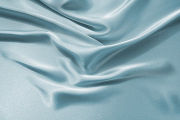 Delicate satin draped fabric of blue color texture for festive backgrounds
