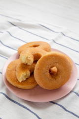 Homemade autumn apple-cinnamon donuts on a pink plate, low angle view. Closeup.