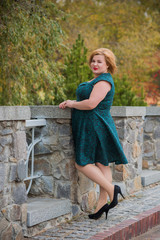 Beautiful mature fashionable woman on a walk in the city. Season time. A nice middle aged plus size woman standing on the street. Plump women lifestyle 