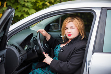 Fototapeta na wymiar Beautiful mature fashionable woman in automobile. A nice middle aged plus size woman driving a car. Plump women lifestyle 