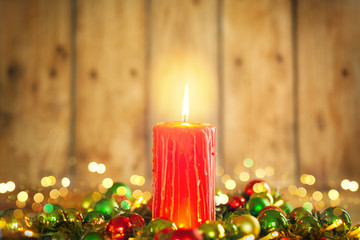 Burning Christmas red candle and  festive Christmas arrangement on a wooden table.