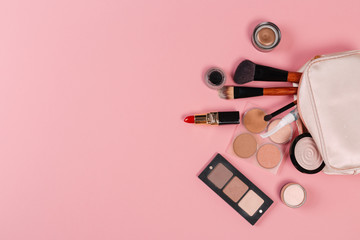 set of decorative cosmetic powder, concealer, eye shadow brush, blush, foundation on pink background