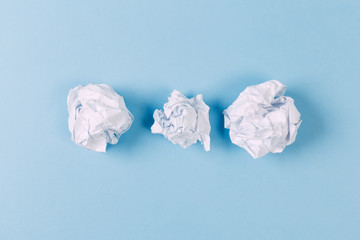 Crumpled paper balls, waste and recycling concept on blue background