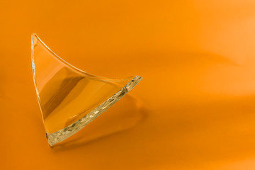 Broken glass dish on orange background. Part of home decoration that was damaged during washing.