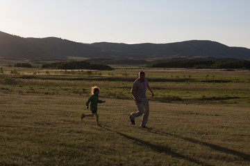 Fototapeta premium dad plays catch-up with daughter at sunset