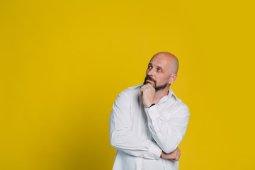 Handsome serious middle aged man meditate on yellow background with copy space.