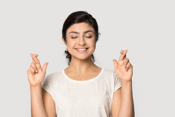 Smiling indian girl cross fingers make wish