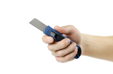 Hand holding a blue stationery knife. Close up. Isolated on white background