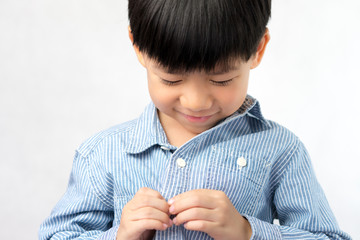 An adorable little asian boy has mistakenly buttoned up wrong, he learning to make it right with a cheerful attitude. Boy getting dress,Montessori,  Life skills, Optimistic, Child development concept.