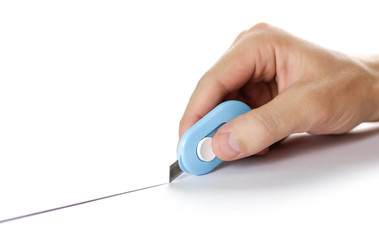 Hand holds a small stationery knife and cuts paper. Close up
