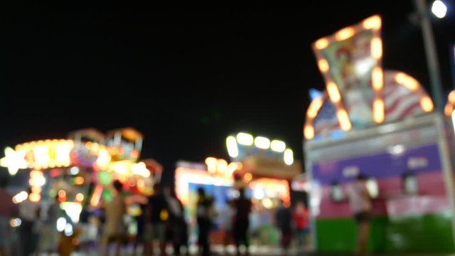Blurred people and tourist in night light funfair.