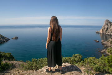 A Nice girl with a high cliff looks out at the sea