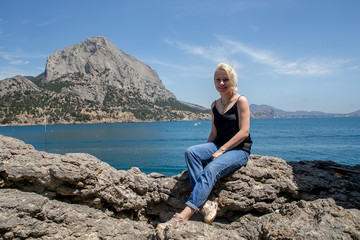 Fototapeta na wymiar nice girl on a rock near the sea