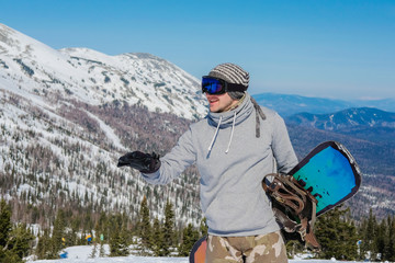 Young snowboarder in the mountains on top. Active rest on a snowboard.