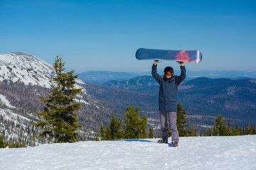 Young snowboarder in the mountains on top. Active rest on a snowboard.