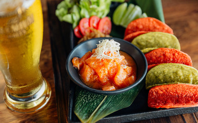 Raw Salmon Spicy Salad served with red and green crispy chips for canape and cold beer.
