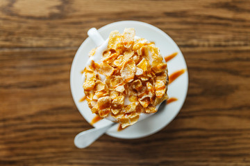 Top view of hot cappuccino topping with cornflakes cereal and caramel butterscotch.