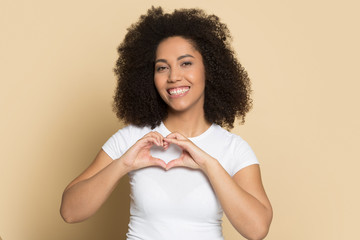 Smiling biracial girl look at camera make heart gesture