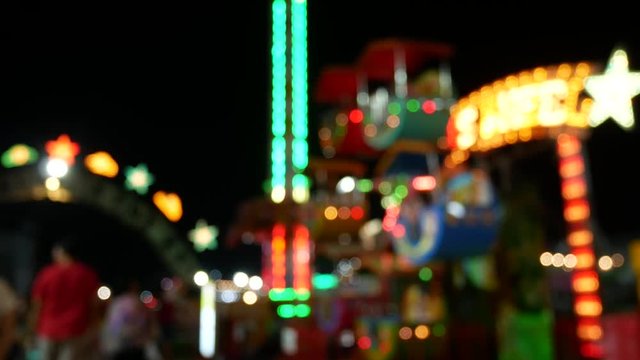 Blurred people and tourist in night light funfair.