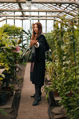 A girl from the school of young wizards with a magic wand in his hand. Green magic. A sorceress conjures among plants in a greenhouse, a botany lesson is cosplay.