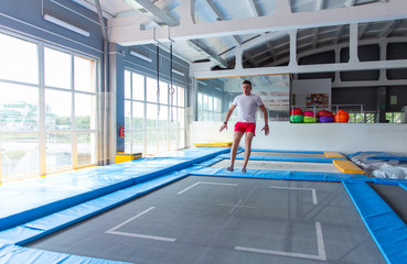 Fitness, fun, leisure and sport activity concept - Handsome happy man jumping on a trampoline indoors