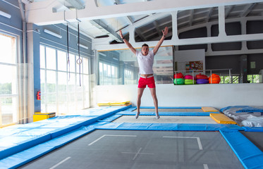 Fitness, fun, leisure and sport activity concept - Handsome happy man jumping on a trampoline...