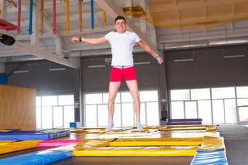 Fitness, fun, leisure and sport activity concept - Handsome happy man jumping on a trampoline...