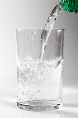 Pouring clear water into glass. Isolated on white background.