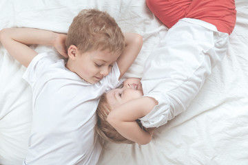 Fototapeta na wymiar children in white t-shirts lie on the bed. brother and sister together