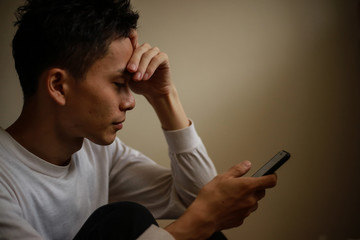 スマートフォンを見て頭を抱える男性