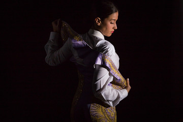 Woman bullfighter by dressing with vest on your back on a black background