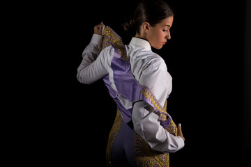 Woman bullfighter by dressing with vest on your back on a black background