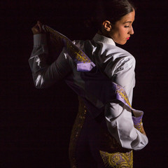 Woman bullfighter by dressing with vest on your back on a black background