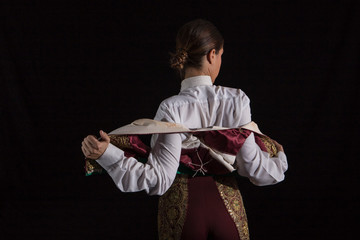 Woman bullfighter by dressing with vest on your back on a black background