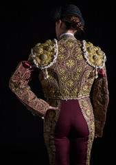 Woman bullfighter by dressing with vest on your back on a black background